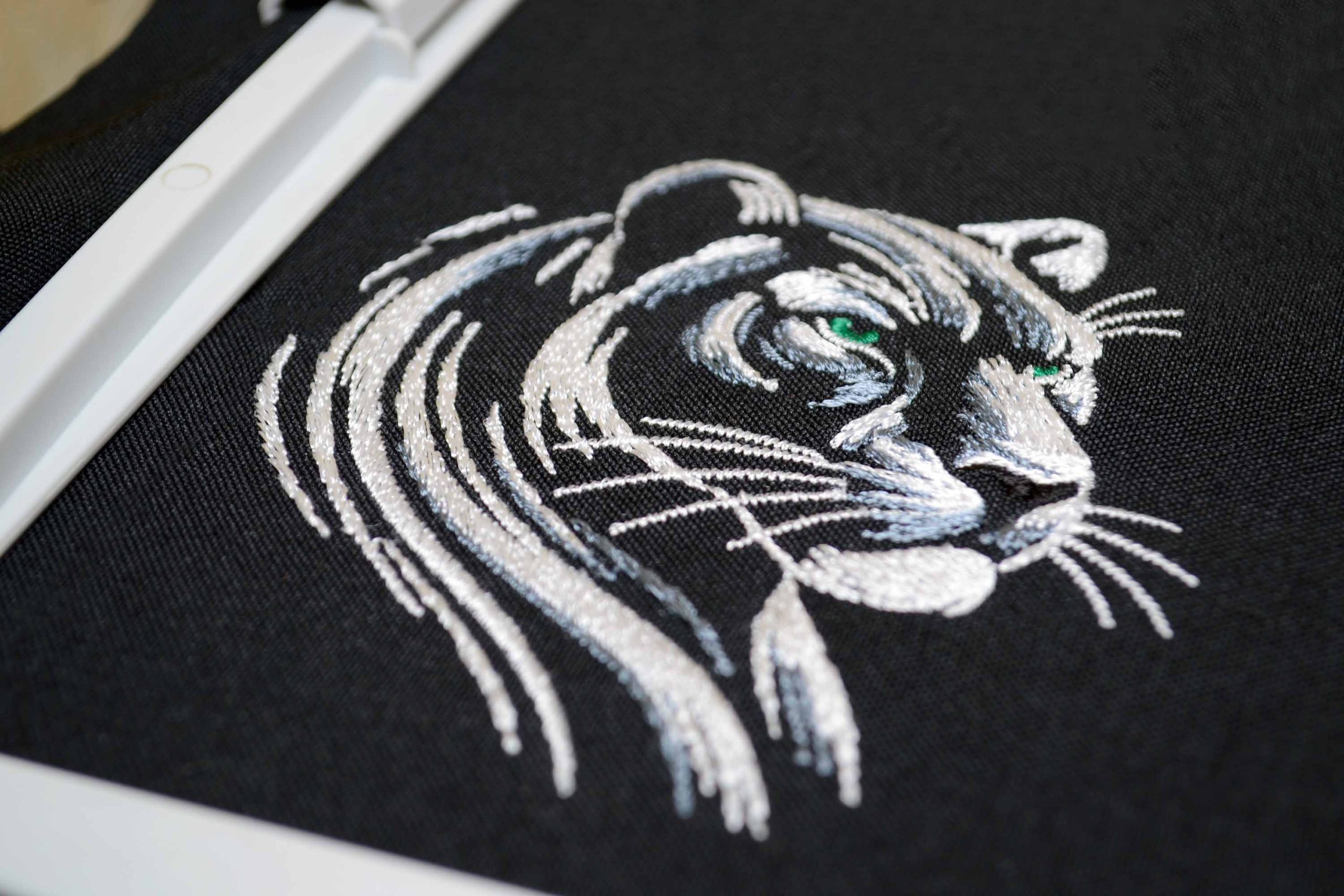 White panther monochrome embroidery on dark fabric White panther monochrome embroidery on dark fabric
